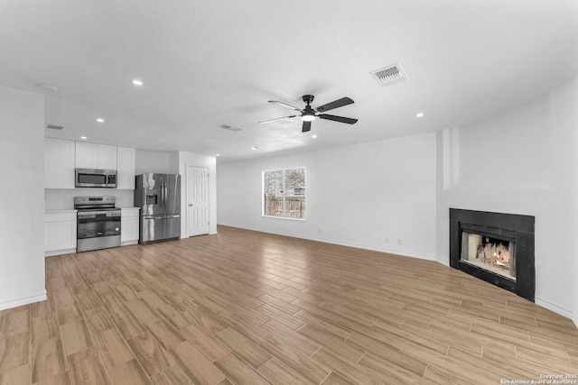 unfurnished living room with ceiling fan and light hardwood / wood-style flooring