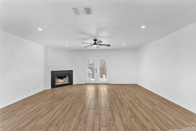 unfurnished living room with ceiling fan, french doors, a textured ceiling, and light wood-type flooring