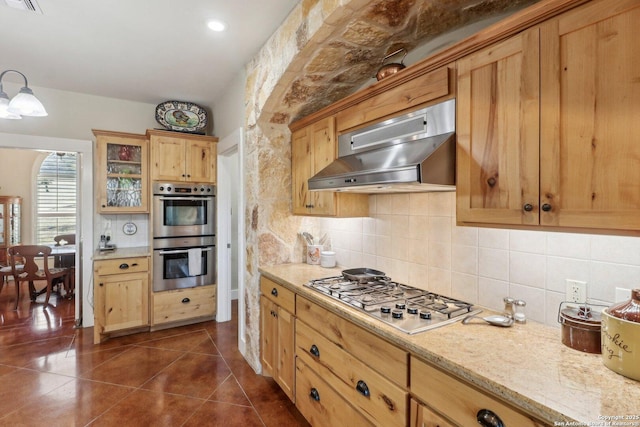 kitchen with tasteful backsplash, appliances with stainless steel finishes, wall chimney exhaust hood, and dark tile patterned flooring