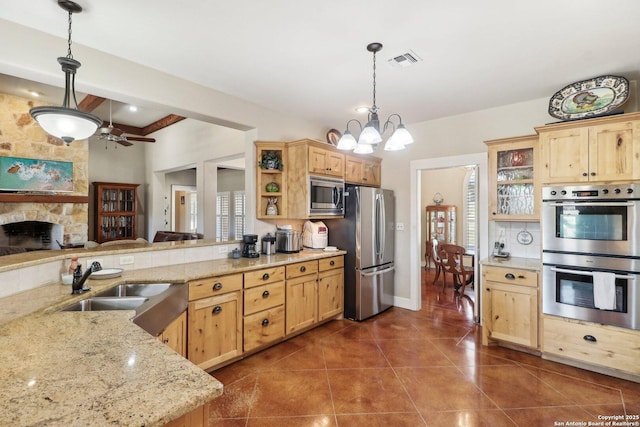 kitchen featuring a fireplace, sink, hanging light fixtures, kitchen peninsula, and stainless steel appliances