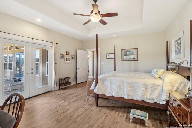 bedroom featuring french doors, light wood-type flooring, access to outside, a raised ceiling, and ceiling fan