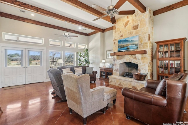 tiled living room with a high ceiling, ceiling fan, a stone fireplace, and beam ceiling