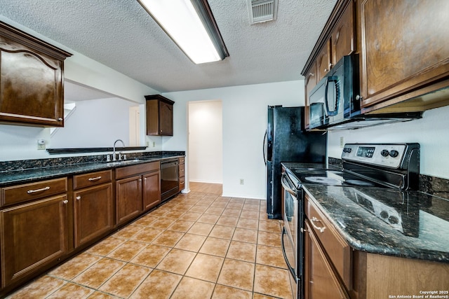 kitchen featuring sink, light tile patterned floors, black appliances, a textured ceiling, and dark stone counters