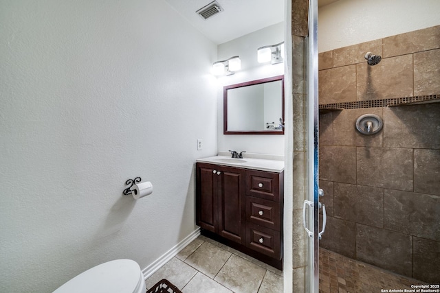 bathroom featuring tile patterned flooring, vanity, a shower with shower door, and toilet