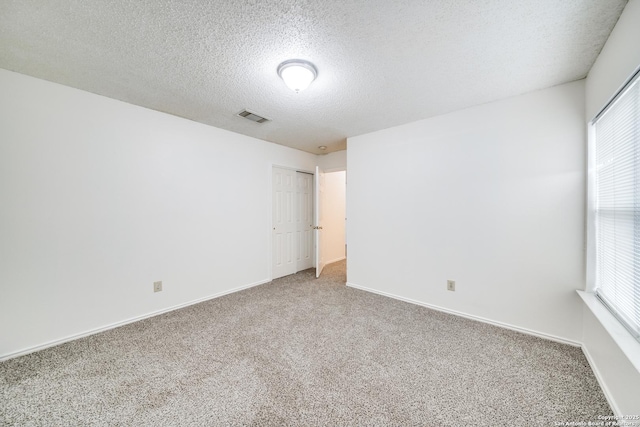 unfurnished room with a textured ceiling and carpet