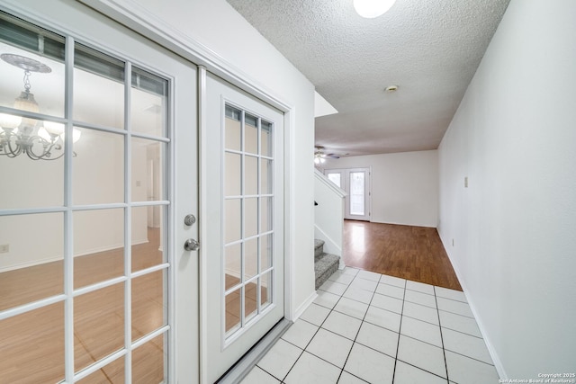 corridor with a notable chandelier, french doors, a textured ceiling, and light tile patterned flooring