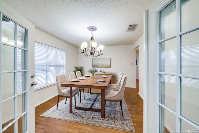 dining room featuring an inviting chandelier, hardwood / wood-style floors, and a textured ceiling