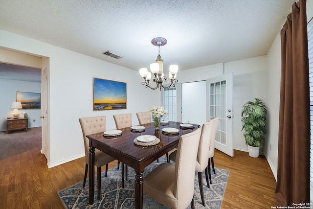 dining area featuring hardwood / wood-style floors, a notable chandelier, and a textured ceiling