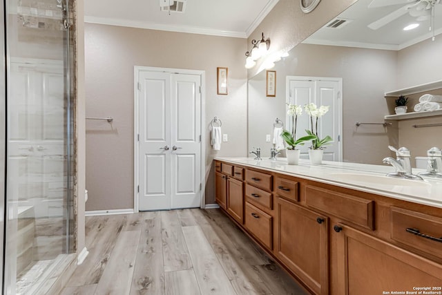 bathroom with wood-type flooring, vanity, ceiling fan, a shower with door, and crown molding