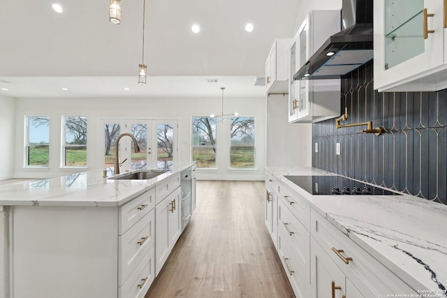 kitchen featuring white cabinetry, wall chimney exhaust hood, black electric cooktop, and pendant lighting