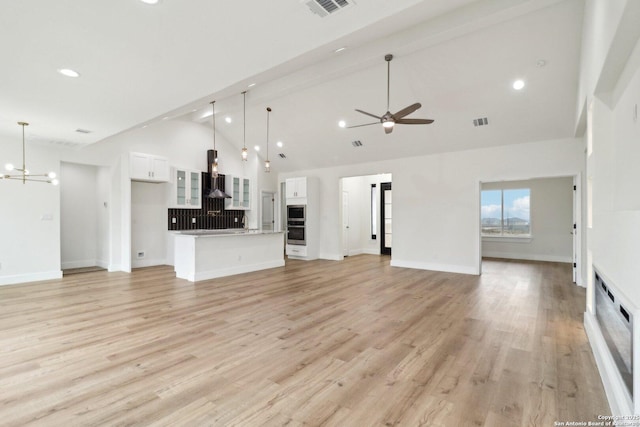 unfurnished living room with beamed ceiling, ceiling fan with notable chandelier, high vaulted ceiling, and light hardwood / wood-style flooring