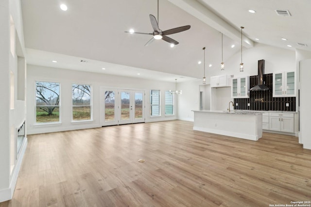 unfurnished living room featuring beamed ceiling, sink, a wealth of natural light, and light wood-type flooring