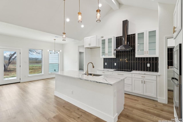 kitchen featuring white cabinetry, sink, decorative light fixtures, and wall chimney exhaust hood