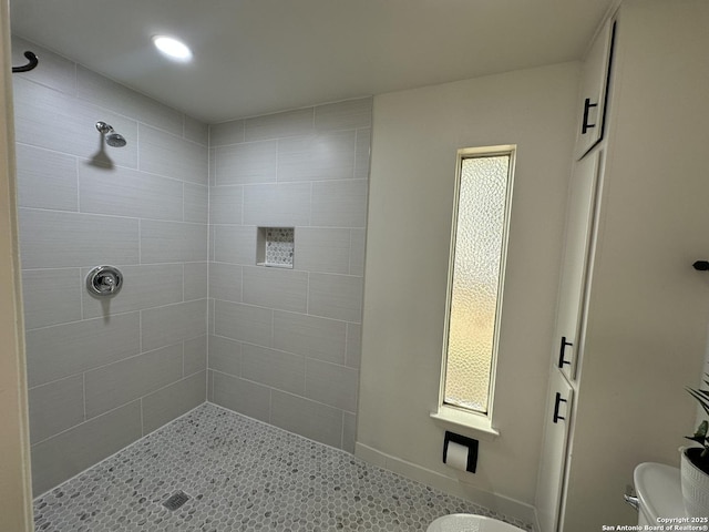 bathroom featuring tiled shower and toilet