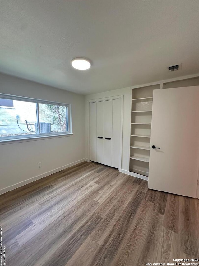 unfurnished bedroom featuring multiple closets, wood-type flooring, and a textured ceiling