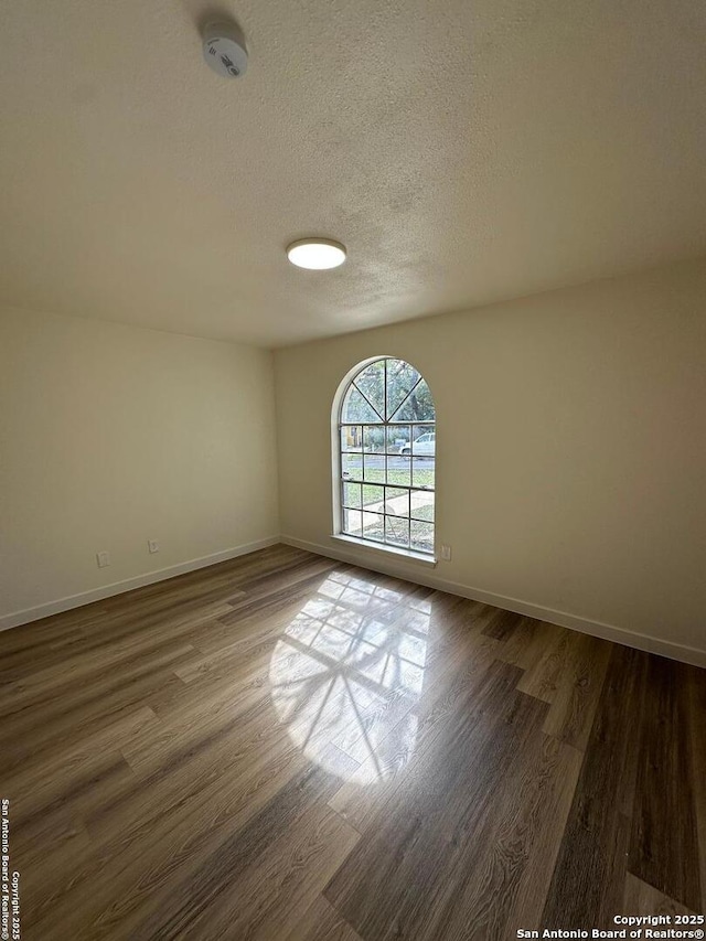 unfurnished room with dark hardwood / wood-style floors and a textured ceiling