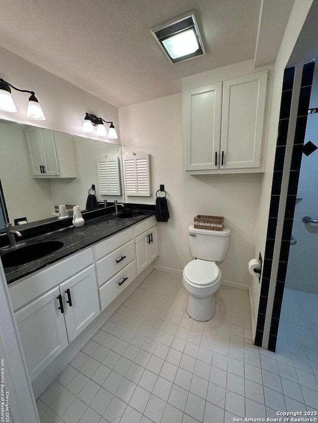 bathroom featuring vanity, tile patterned flooring, toilet, and walk in shower