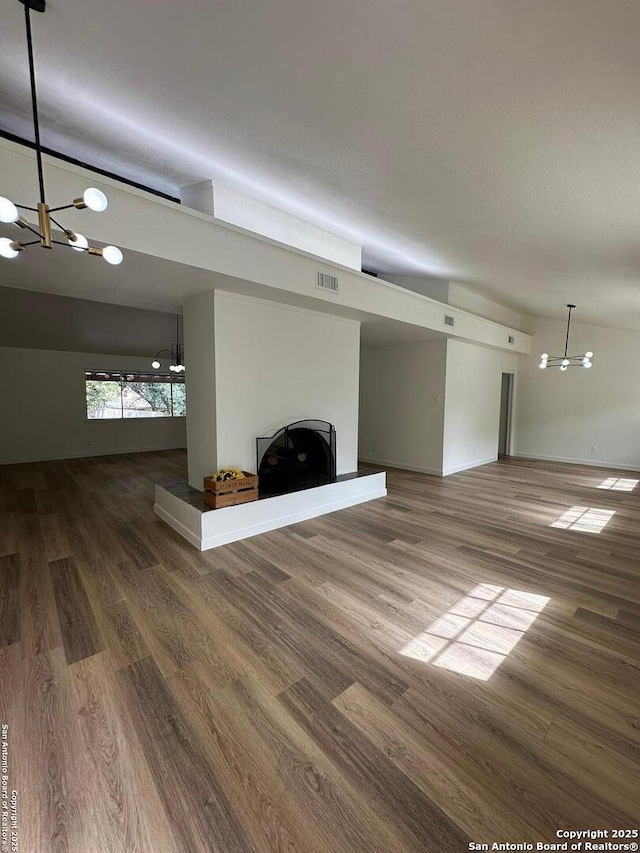 unfurnished living room with lofted ceiling, a chandelier, and hardwood / wood-style floors