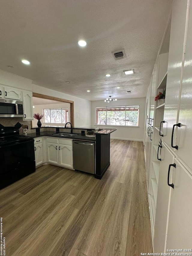 kitchen with sink, light hardwood / wood-style flooring, stainless steel appliances, white cabinets, and kitchen peninsula