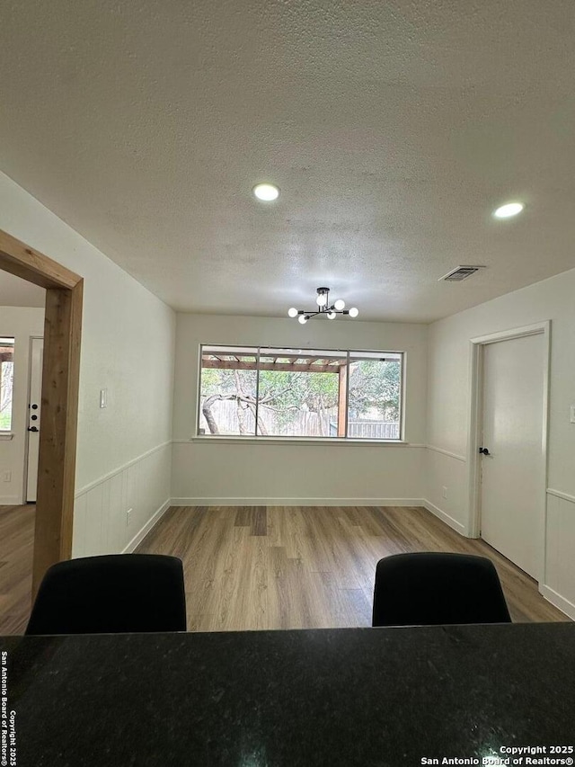 interior space featuring an inviting chandelier, hardwood / wood-style floors, and a textured ceiling