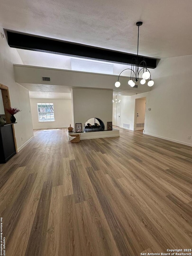 unfurnished living room with beam ceiling, a textured ceiling, and hardwood / wood-style flooring