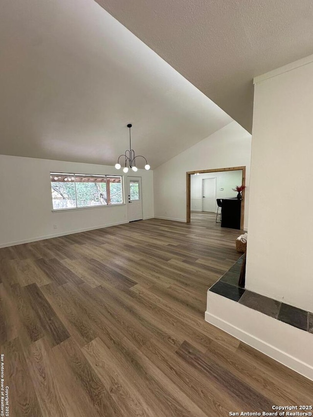 empty room featuring lofted ceiling, a textured ceiling, dark hardwood / wood-style floors, and a chandelier