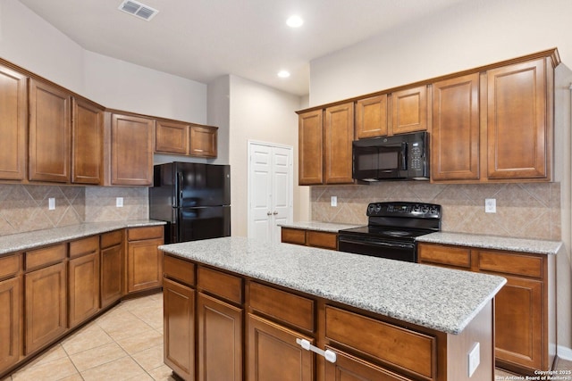 kitchen with tasteful backsplash, light stone countertops, black appliances, and a kitchen island