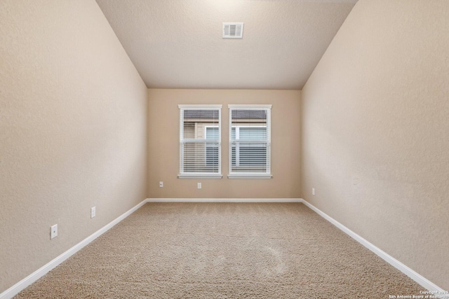 empty room featuring vaulted ceiling, carpet floors, and a textured ceiling