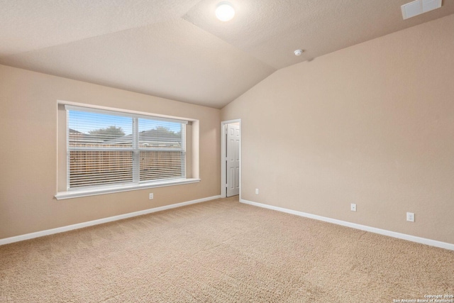 spare room featuring lofted ceiling, a textured ceiling, and carpet flooring