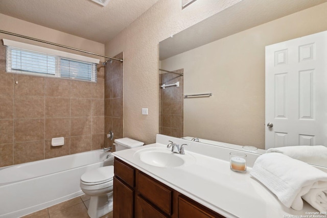 full bathroom featuring tiled shower / bath, vanity, toilet, tile patterned floors, and a textured ceiling