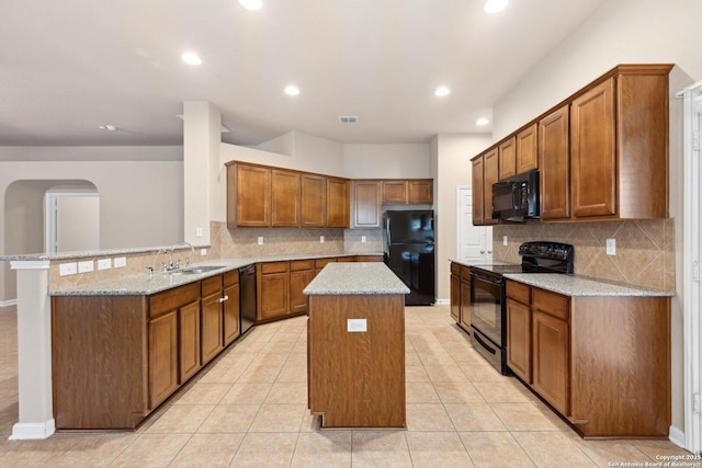 kitchen with light stone countertops, a kitchen island, kitchen peninsula, and black appliances