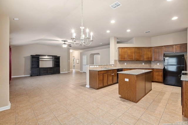 kitchen with hanging light fixtures, tasteful backsplash, black fridge, ceiling fan with notable chandelier, and kitchen peninsula