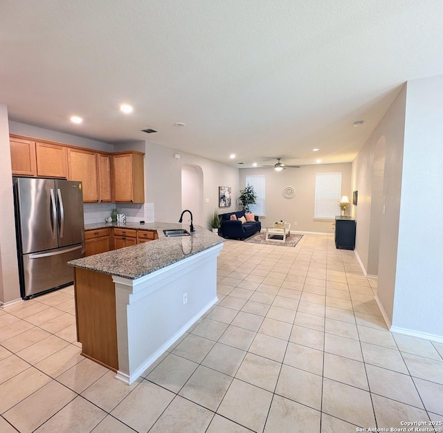 1410 Hummingbird, San Antonio, TX 78245 - kitchen with sink, light tile patterned floors, stainless steel refrigerator, kitchen peninsula, and dark stone counters