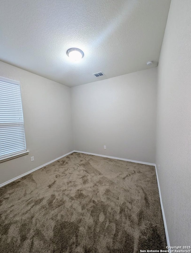 carpeted empty room with a textured ceiling