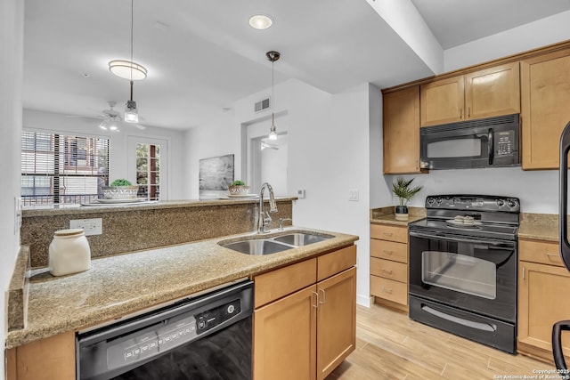 kitchen featuring sink, hanging light fixtures, light hardwood / wood-style floors, black appliances, and light stone countertops