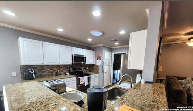 kitchen featuring appliances with stainless steel finishes, white cabinetry, sink, backsplash, and light stone countertops