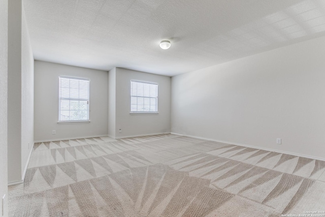 carpeted empty room featuring a textured ceiling