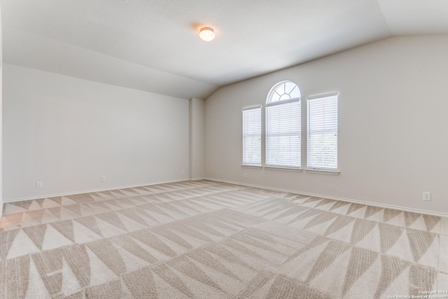 carpeted spare room with lofted ceiling