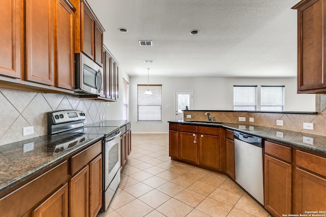 kitchen with sink, hanging light fixtures, light tile patterned floors, appliances with stainless steel finishes, and backsplash