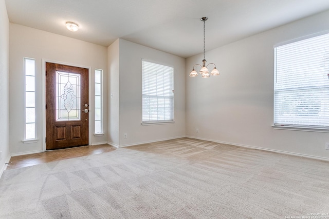 entrance foyer with light colored carpet and a notable chandelier