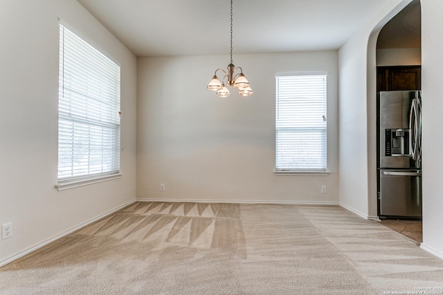 unfurnished dining area featuring light carpet and a chandelier