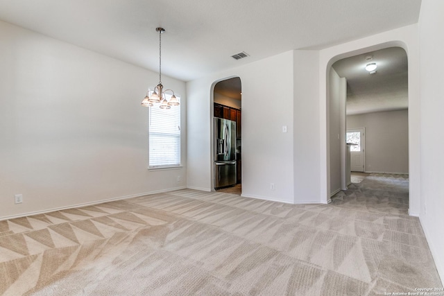 carpeted spare room featuring a chandelier