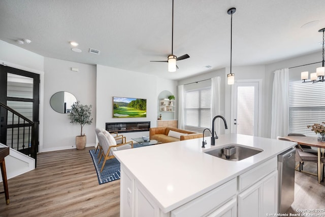 kitchen with sink, white cabinetry, a center island with sink, dishwasher, and pendant lighting