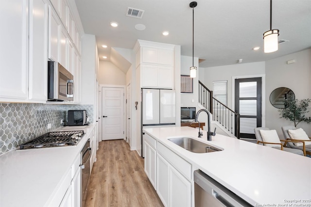 kitchen featuring hanging light fixtures, appliances with stainless steel finishes, sink, and white cabinets