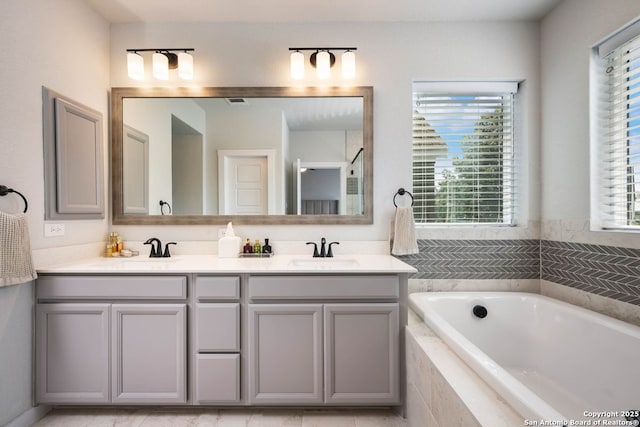 bathroom with tiled tub and vanity