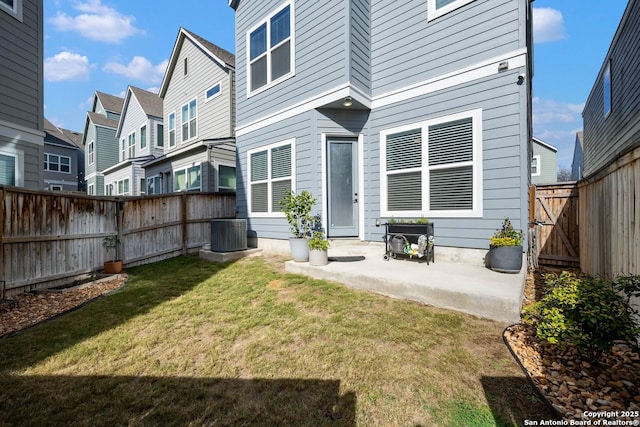 back of house featuring cooling unit, a patio, and a lawn