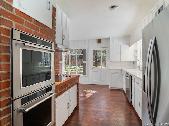 kitchen with white cabinetry, backsplash, and stainless steel appliances