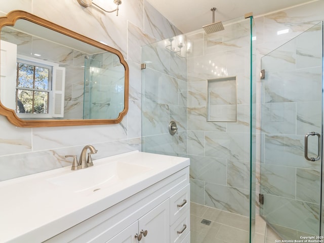 bathroom featuring vanity, a shower with door, tile walls, and backsplash