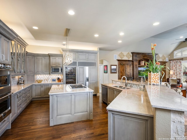 kitchen featuring a large island with sink, sink, built in appliances, and gray cabinetry