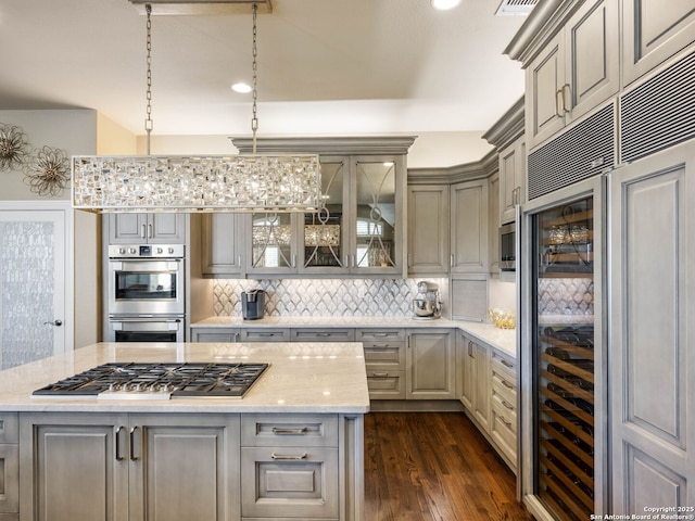 kitchen featuring gray cabinets, dark hardwood / wood-style floors, decorative backsplash, light stone counters, and stainless steel appliances